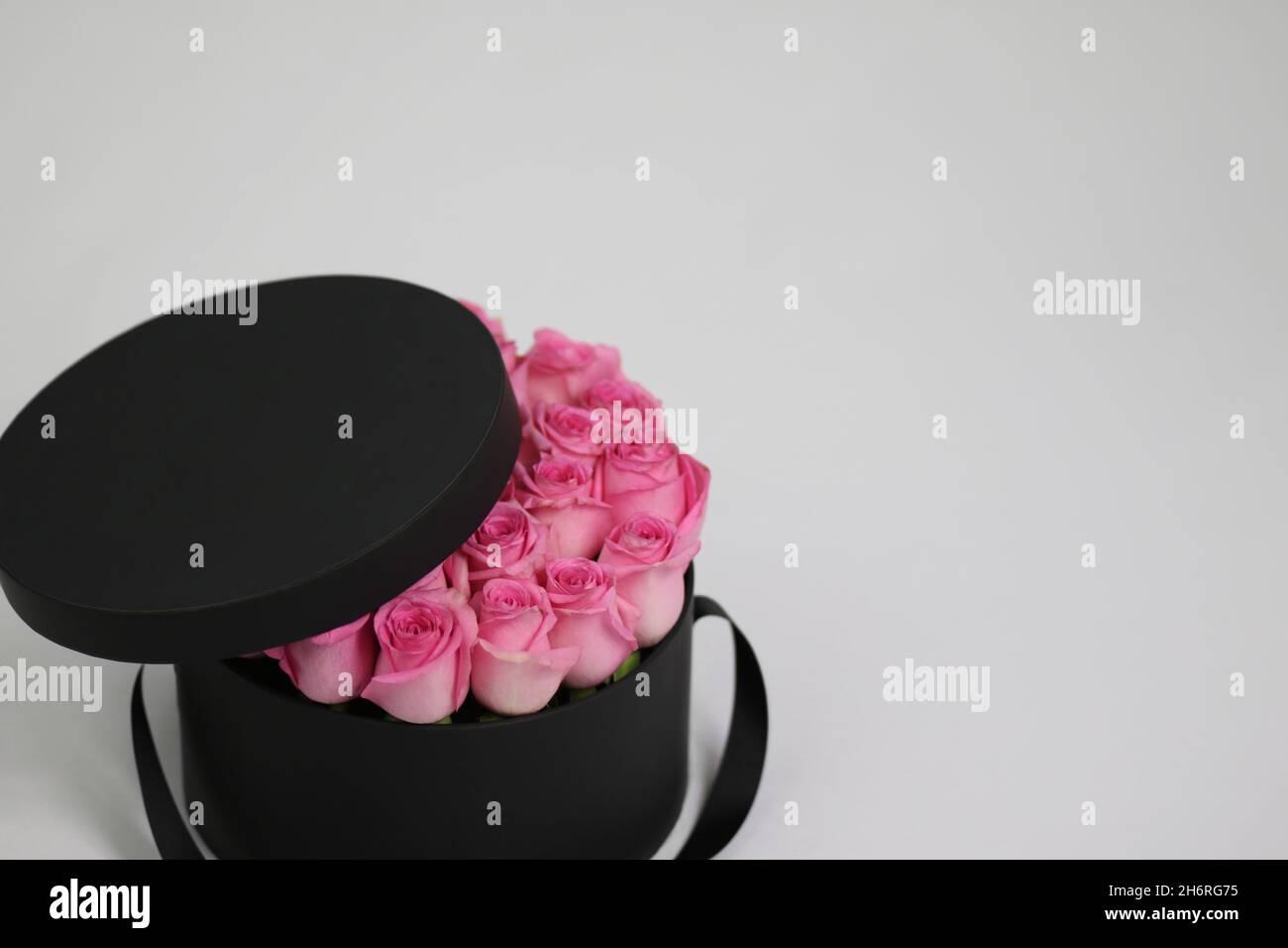 Caja negra redonda de regalo de flores con rosas rosadas en el interior y  tapa abierta. Elegante arreglo floral Fotografía de stock - Alamy