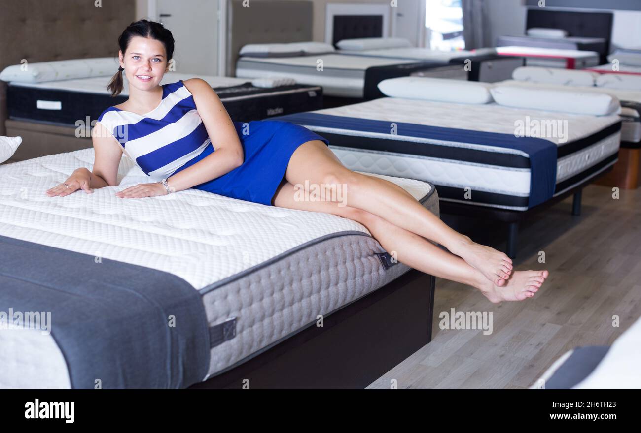 La mujer joven está probando el colchón en el tiempo acostada en la cama  Fotografía de stock - Alamy