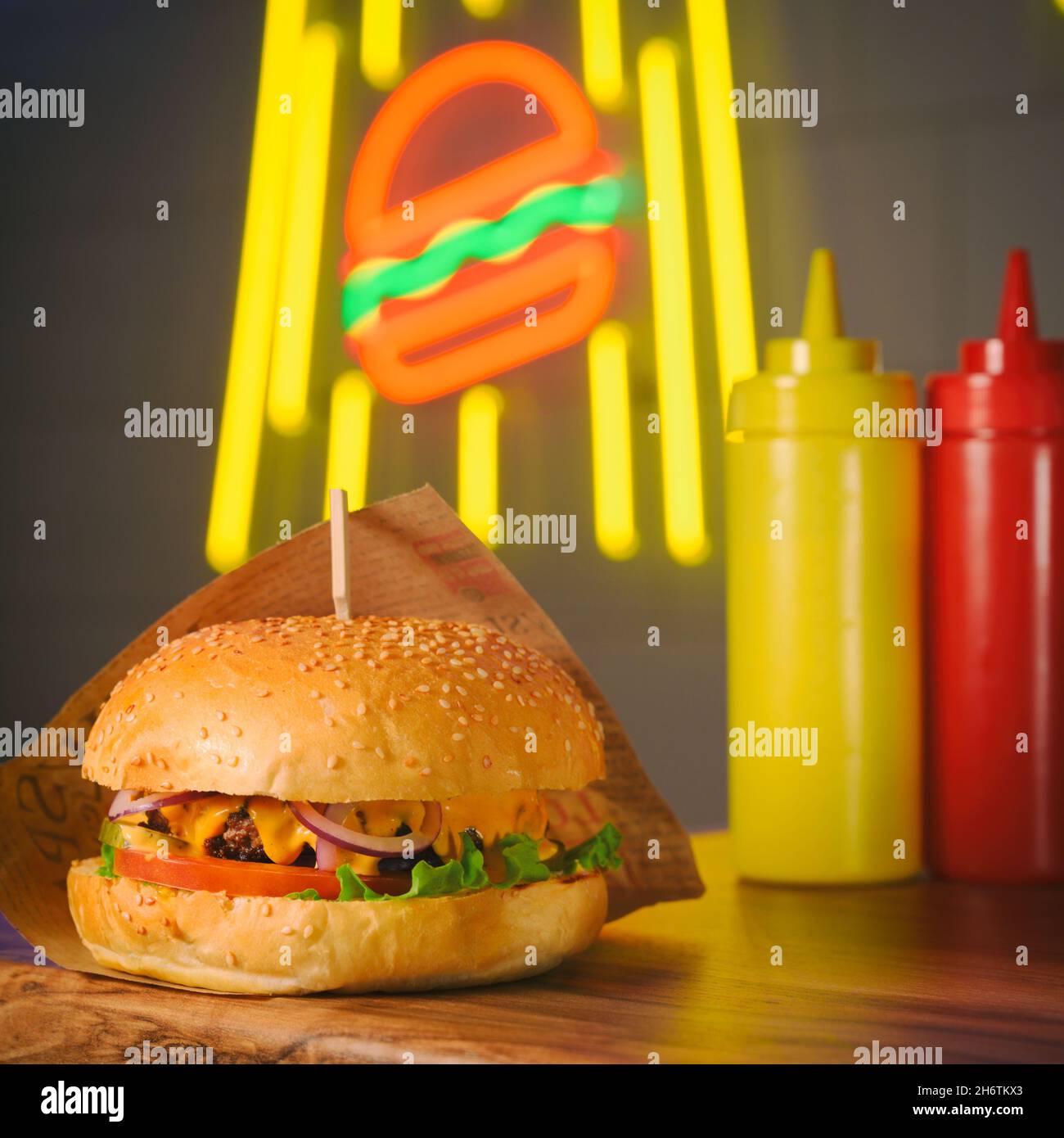 hamburguesa con dos botellas de salsa en la luz de neón hamburguesa en la cafetería nocturna Foto de stock