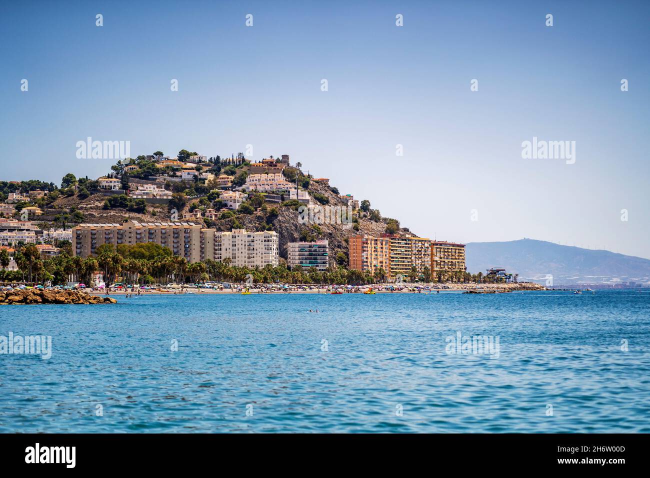 Paisaje urbano de Almunecar - casas en colinas empinadas por la costa y la concurrida playa, Andalucía, España Foto de stock