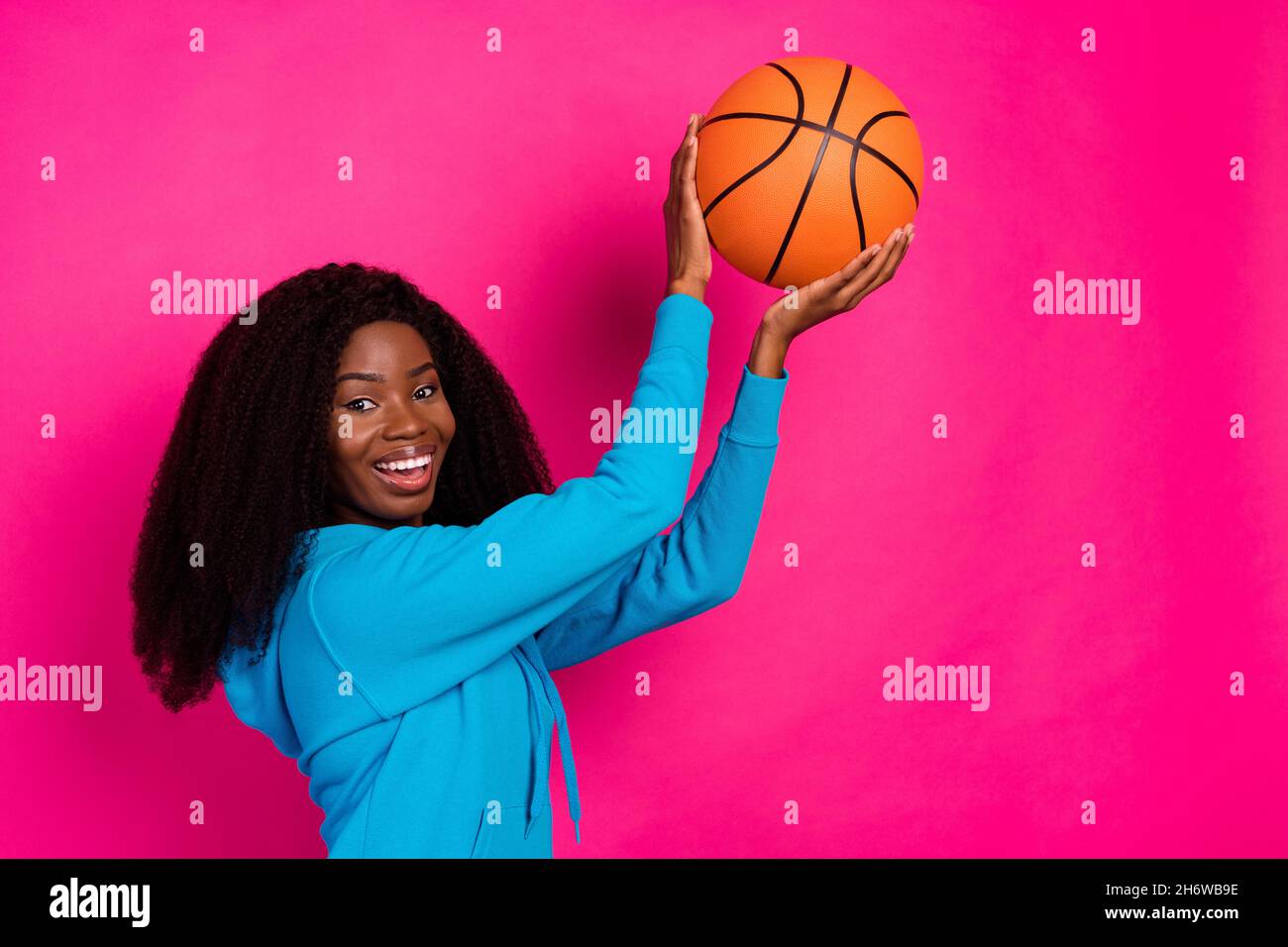 Joven Mujer afroamericana en vestimenta deportiva y tacones altos sentados  en las escaleras de madera en la cancha de deportes y sosteniendo una  pelota de baloncesto Fotografía de stock - Alamy