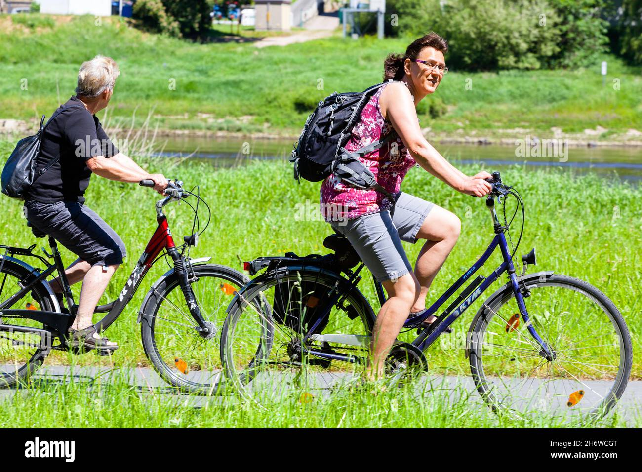Dos mujeres mayores montando en bicicleta a lo largo del río Elba Alemania Sajonia Exterior Vida saludable Foto de stock
