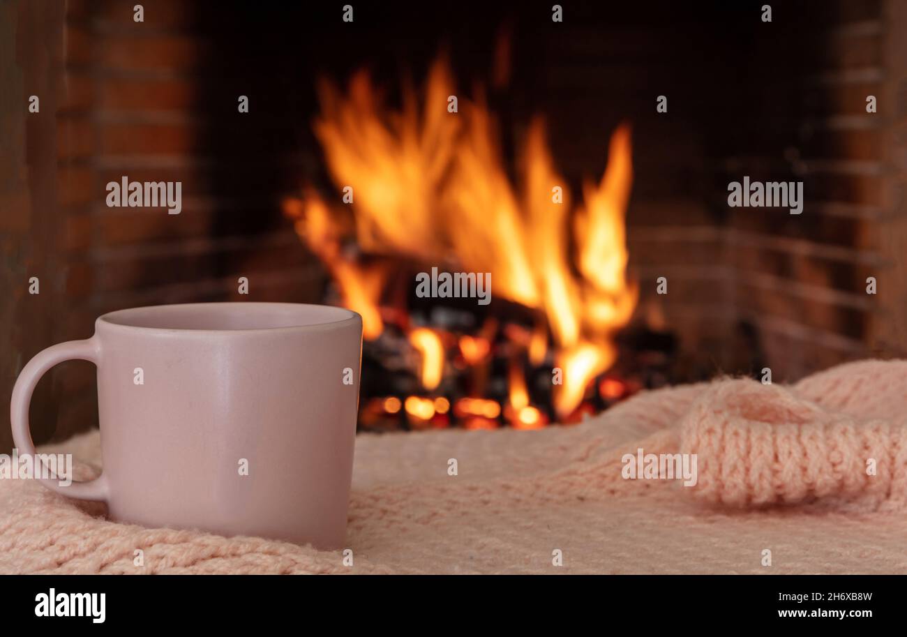Taza de café en una manta de sofá, chimenea de fondo. Taza de té de color  rosa, relajación junto al fuego, vacaciones de Navidad acogedor hogar  cálido Fotografía de stock - Alamy