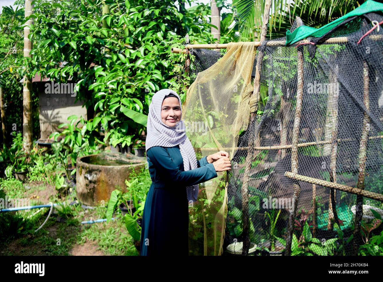Una mujer musulmana cierra la planta de la casa en la escena rural Foto de stock