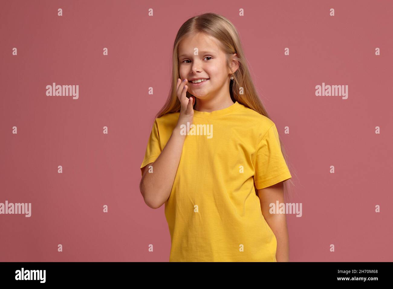 niña pequeña en una camiseta amarilla, con aspecto shyly