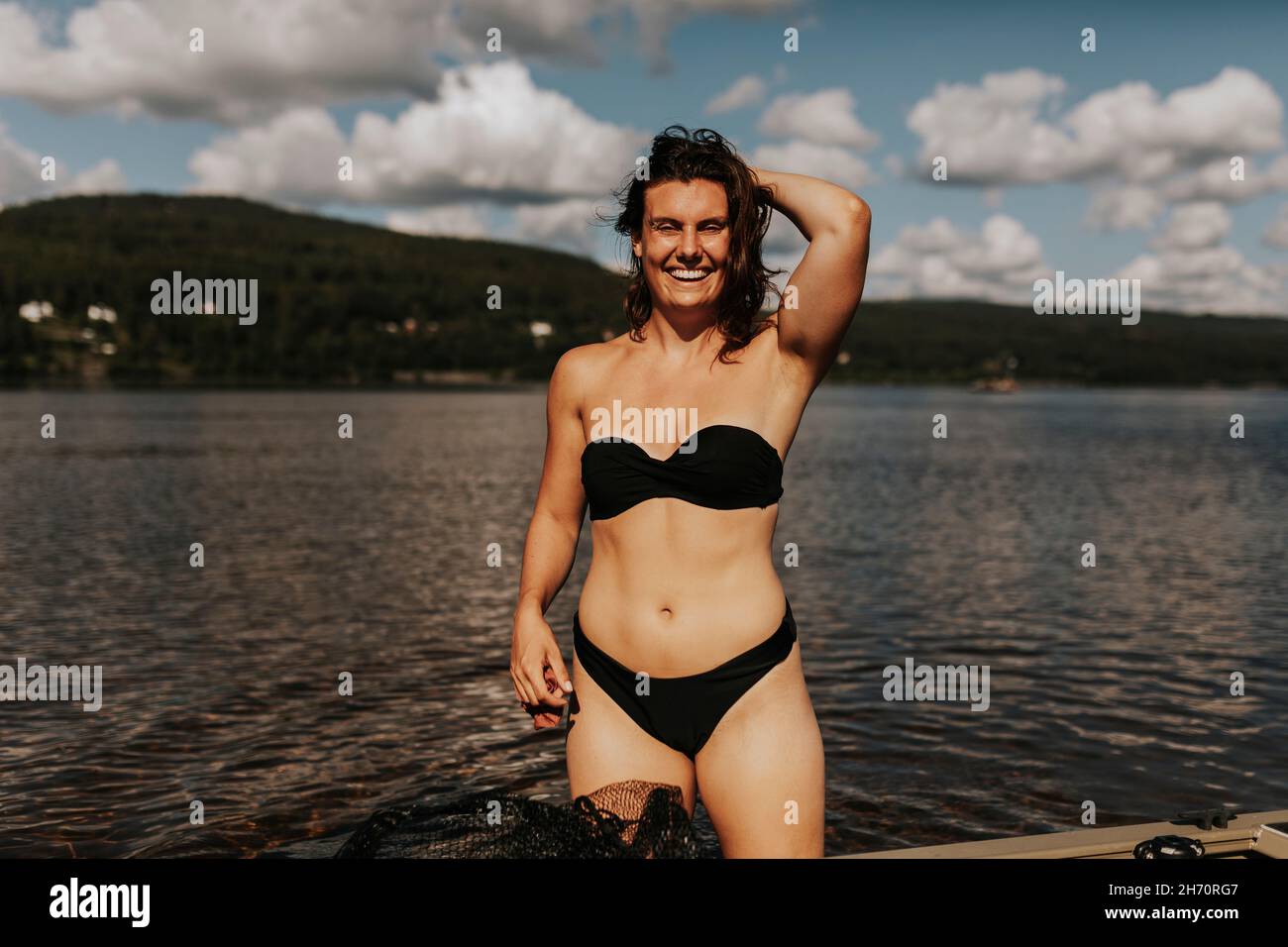 Mujer sonriente en el lago mirando la cámara Foto de stock
