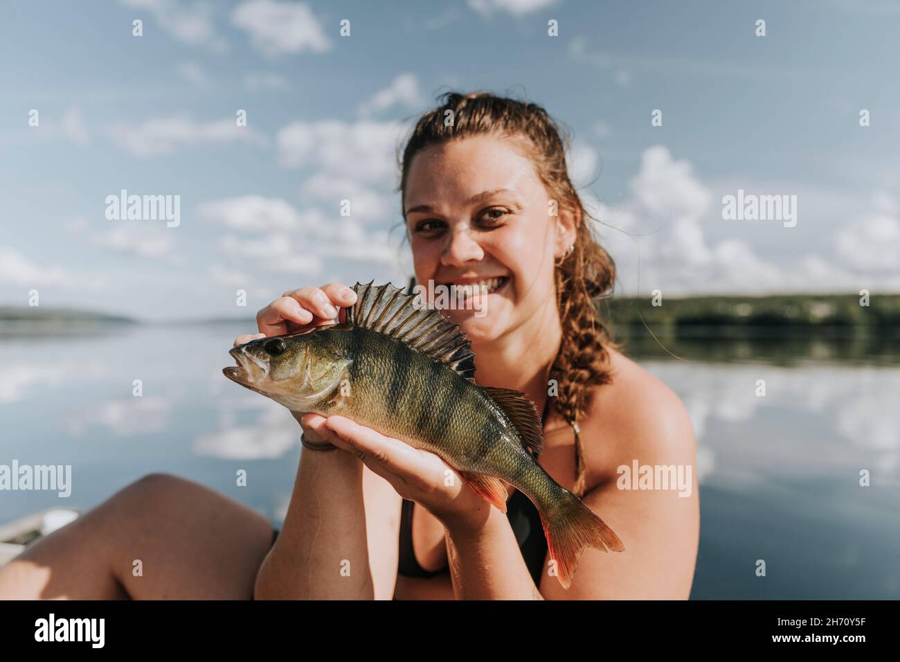 Mujer sonriente en el barco sosteniendo pescado Foto de stock