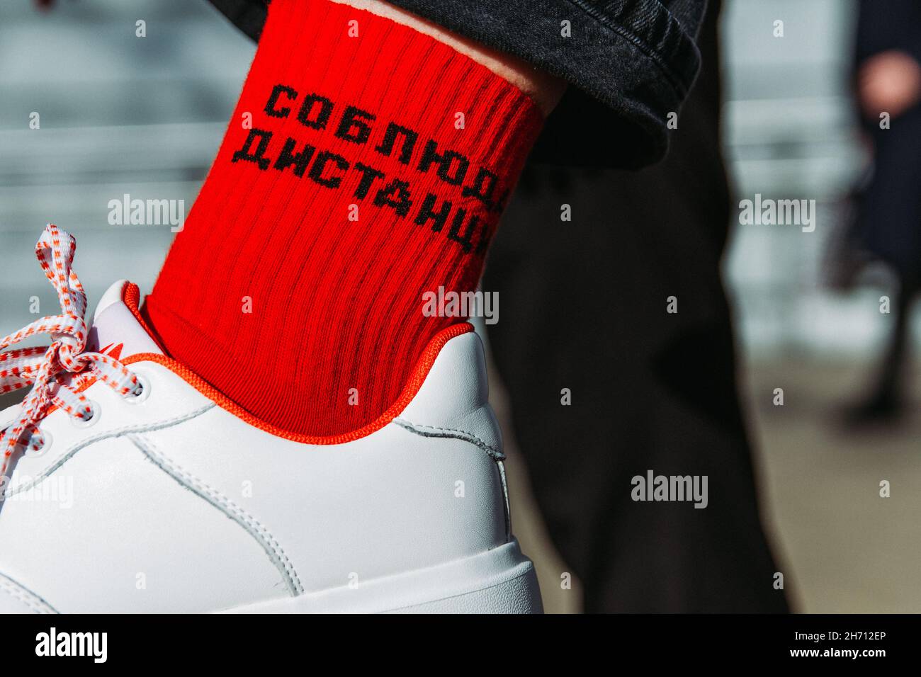Disparo de enfoque selectivo de un pie con zapatillas de deporte blancas y  calcetines rojos, traducción: 'Mantener distancia' Fotografía de stock -  Alamy