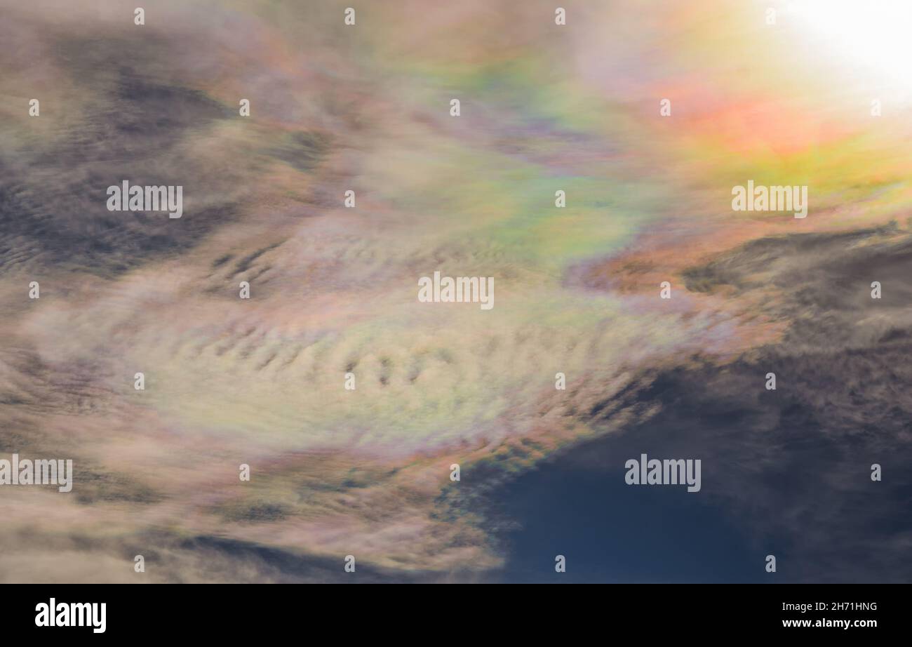 La iridiscencia de la nube es un fenómeno de difracción de colores causado por pequeños cristales de hielo que dispersan individualmente la luz en nubes delgadas a 10 grados de distancia Foto de stock