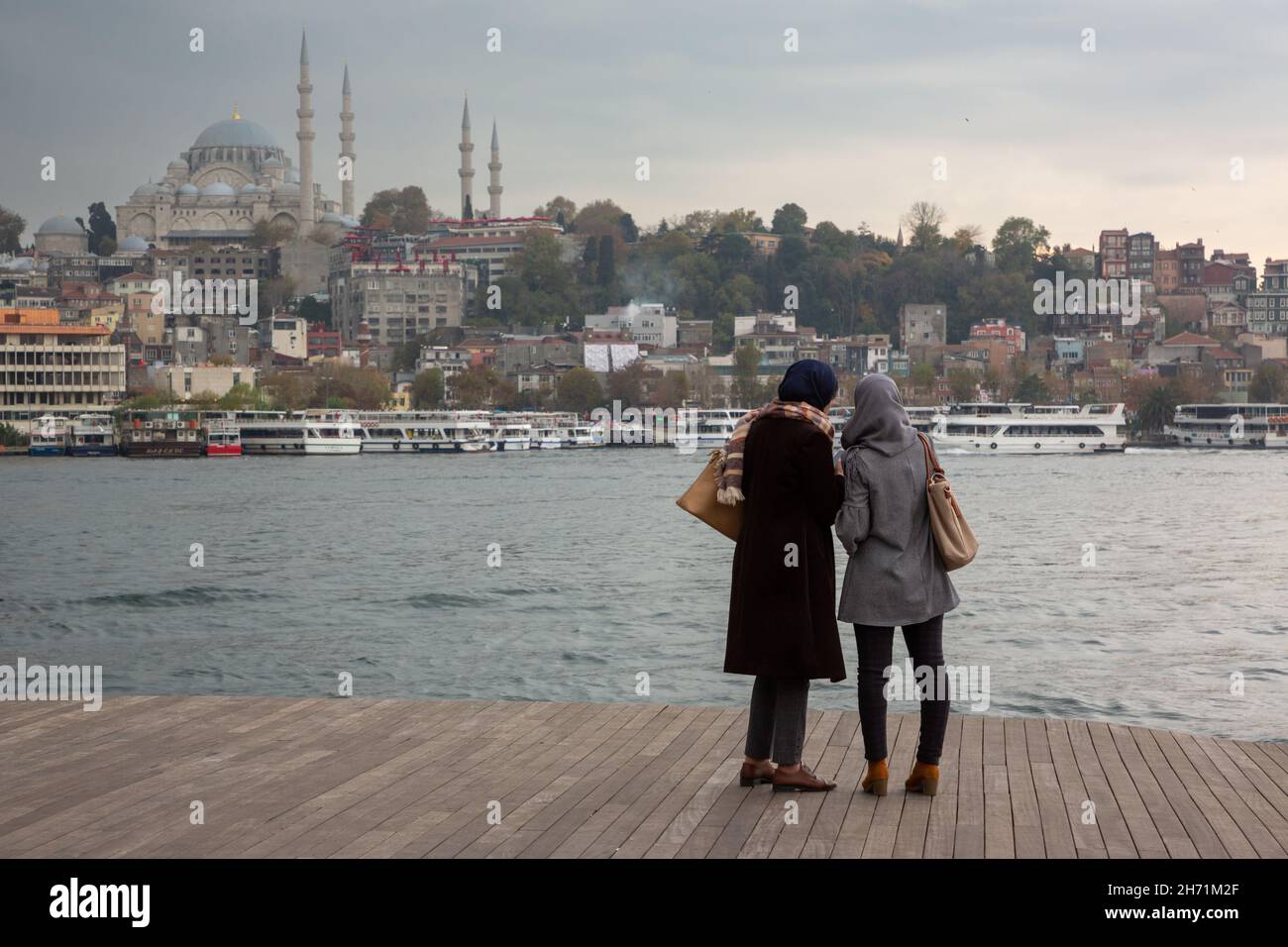 Dos amigas están viendo la vista de Estambul mientras se encuentran en el Cuerno de Oro y charlando Foto de stock