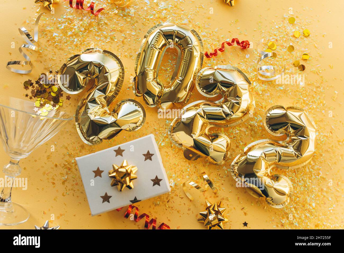 Globos hechos de papel de aluminio en forma de números 2022 con confeti sobre fondo de oro . Celebración de Navidad, Año Nuevo y concepto festivo. Plano, vista superior. Foto de stock