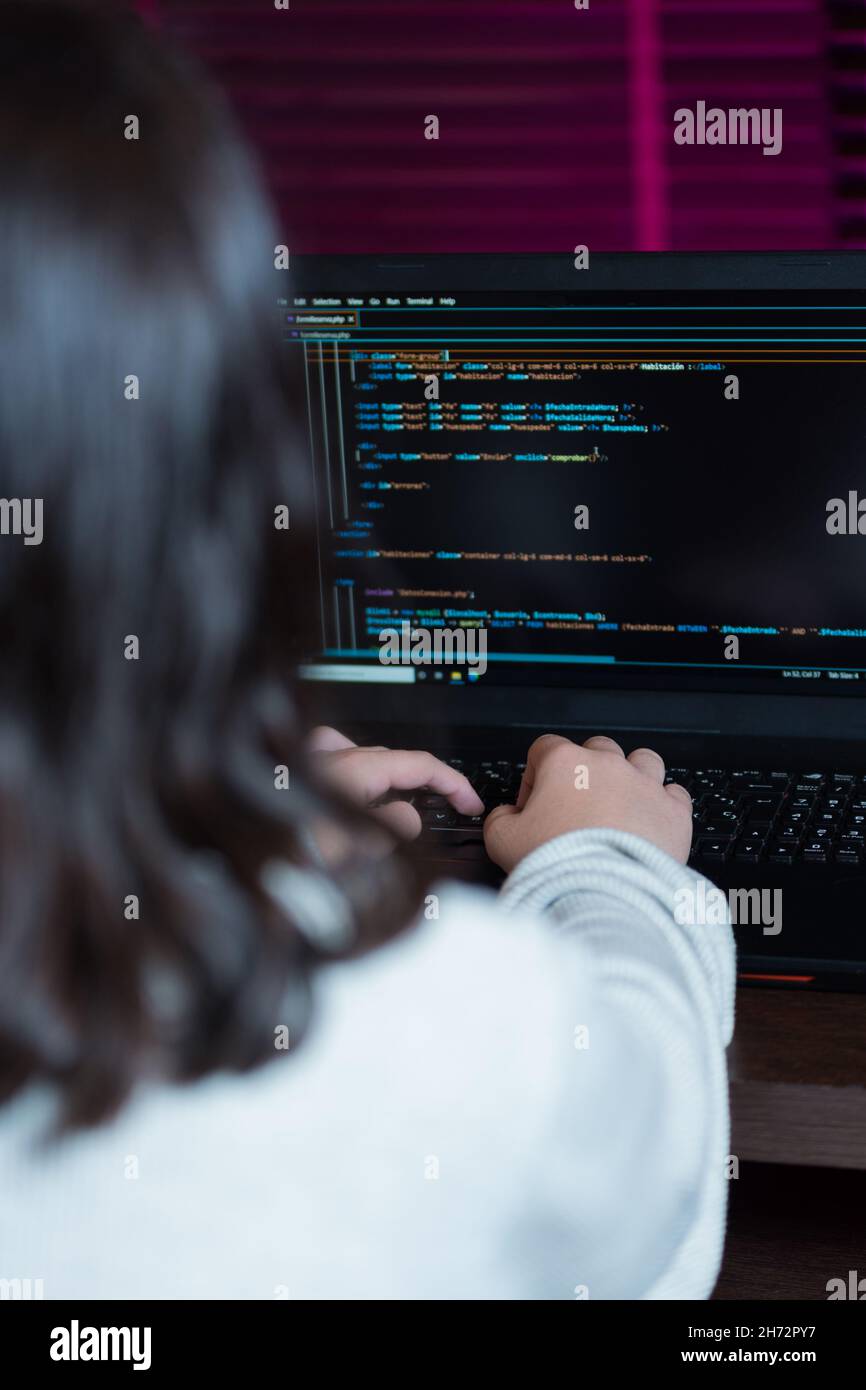 Imagen vertical de una adolescente escribiendo código para programar una aplicación web. Foto de stock