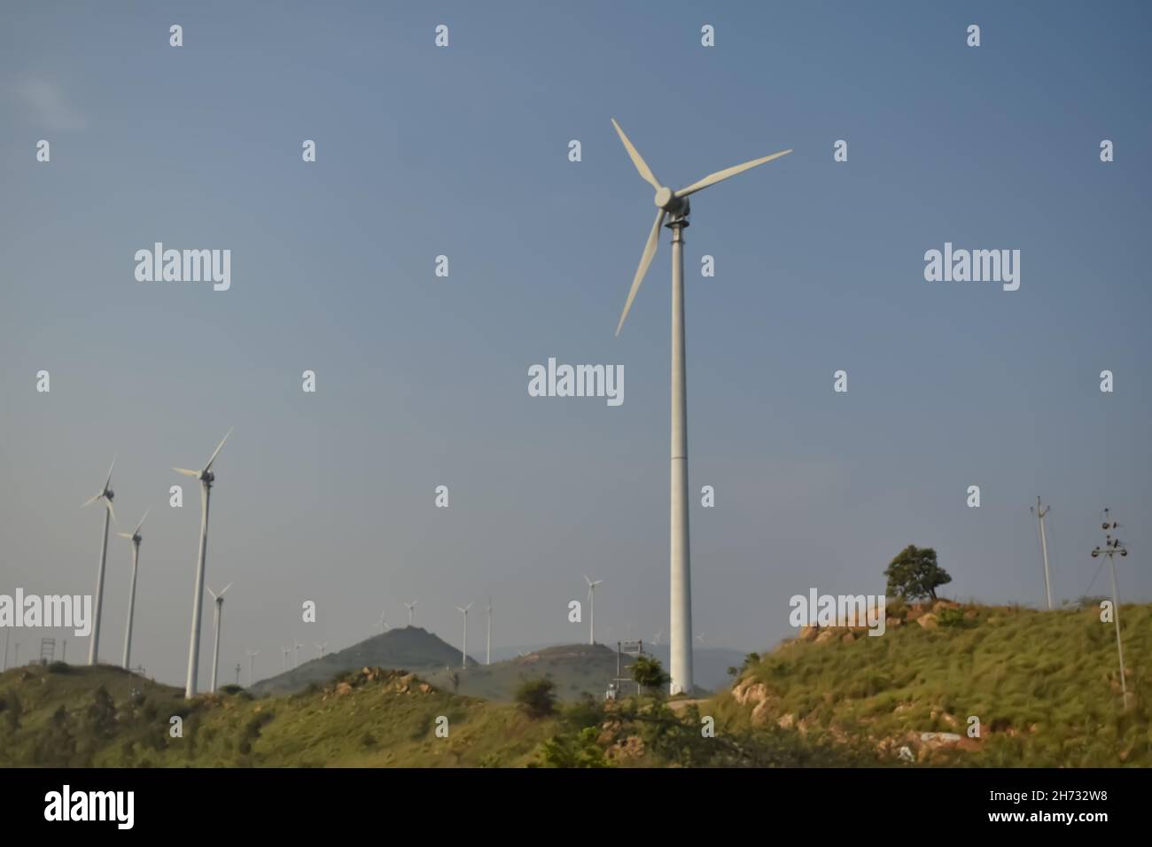 Foto de enfoque selectivo de múltiples molinos de viento que son fuente de energía renovable que funcionan en la parte superior Foto de stock
