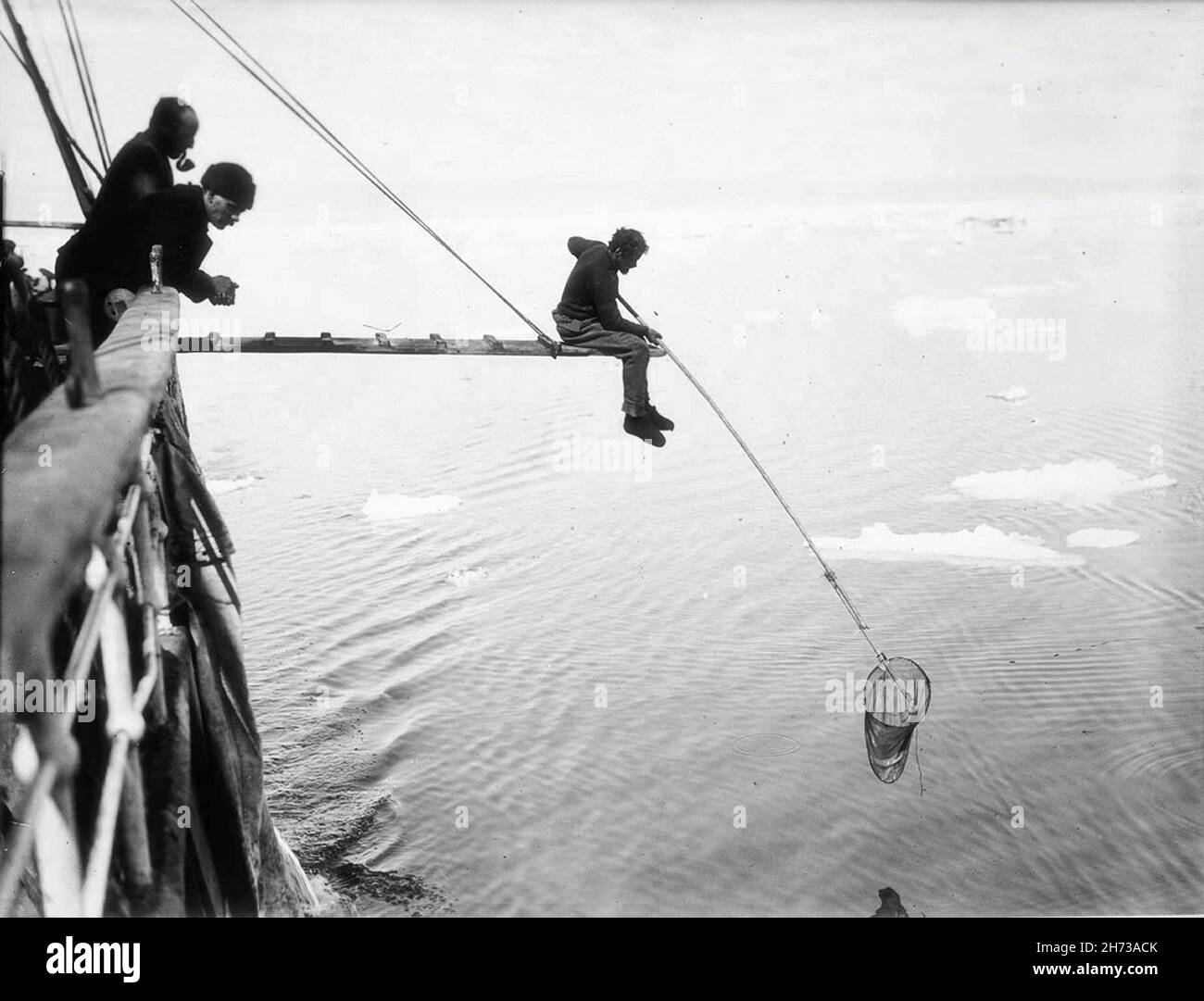 Miembros de la tripulación que pescan desde la cubierta de Endurance, en el épico viaje de Ernest Sjackleton a la Antártida en 1912 Foto de stock