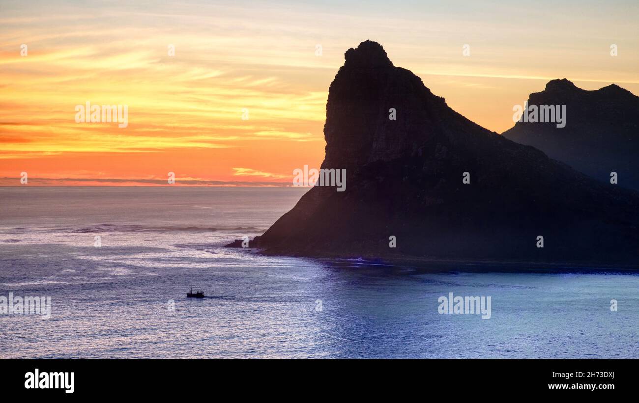 Un barco de pesca que sale de Hout Bay, cerca de Ciudad del Cabo en Sudáfrica, al atardecer. Visto desde Chapman's Peak. Foto de stock