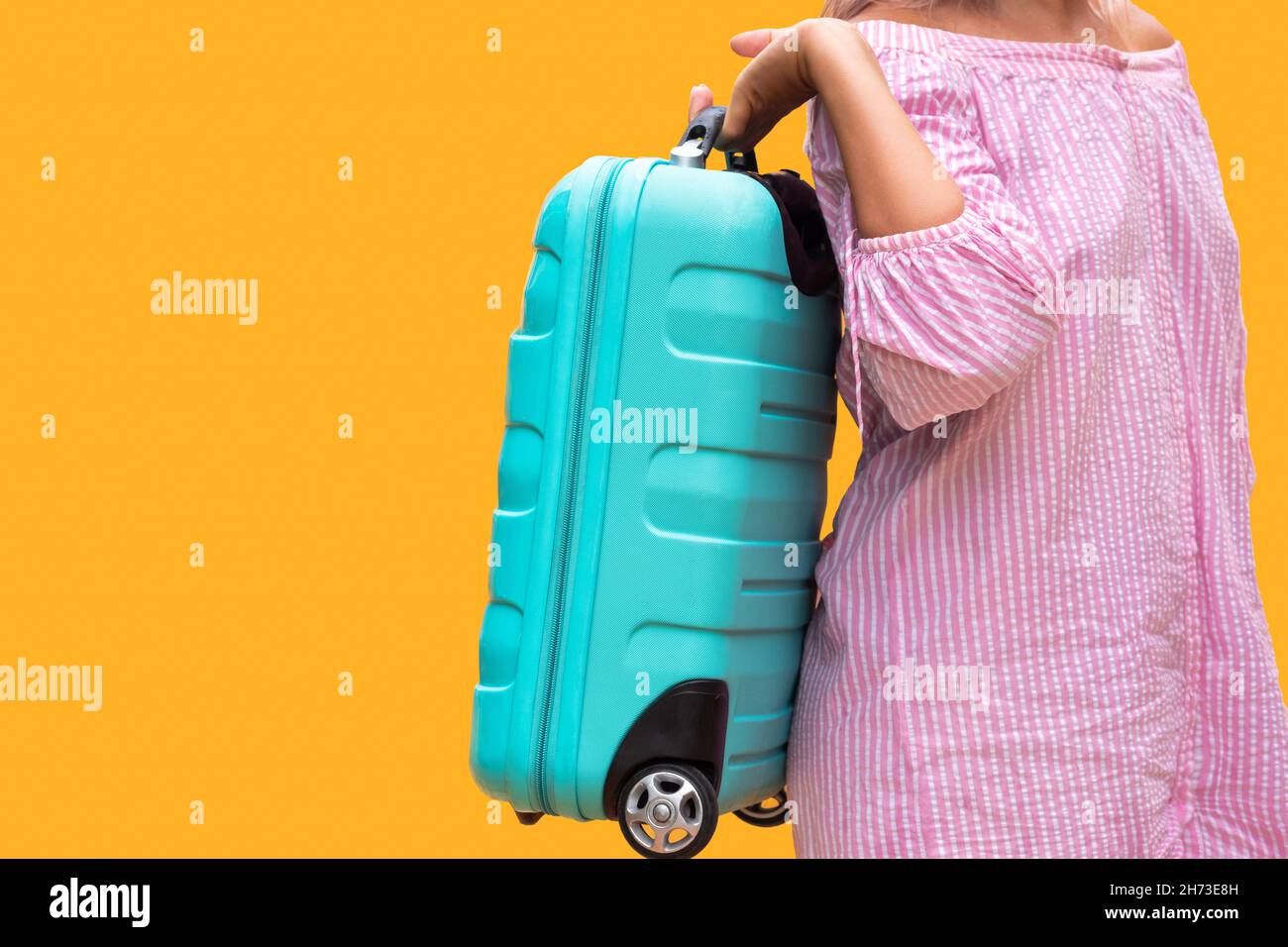 Maleta de viaje de plástico turquesa. La chica de vestido rosa lleva una  bolsa sobre el fondo amarillo naranja. Va de viaje Fotografía de stock -  Alamy