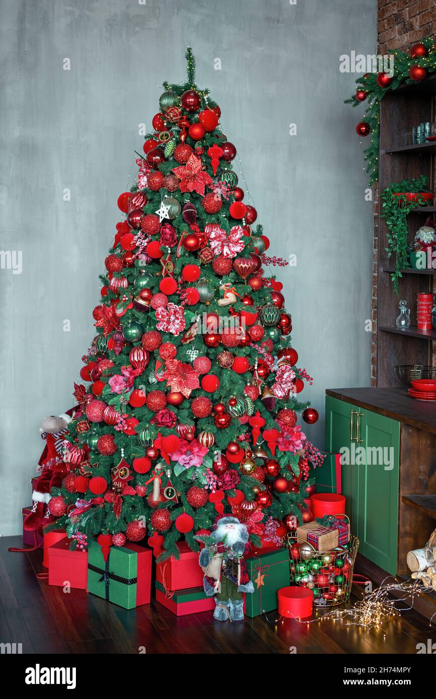 Árbol de Navidad decorado con bolas rojas y verdes, juguetes y ornatos en  un interior oscuro. Abeto de Año Nuevo decorado con los regalos y cajas  brillantes. Disparo vertical Fotografía de stock -