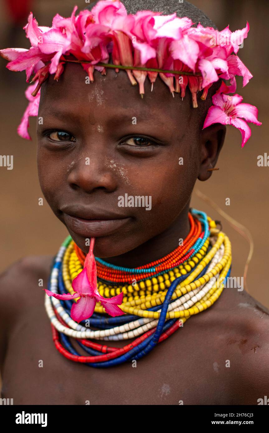 Joven de la tribu Karo con coloridas cuentas y flores en su cabeza para decoración Foto de stock