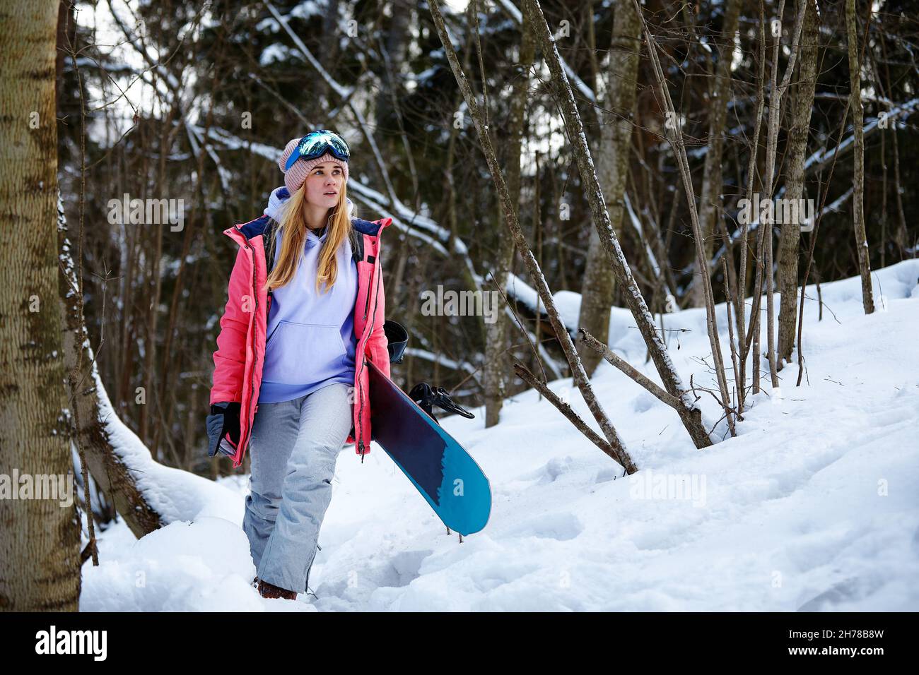 imagen con un retrato de una snowboarder mujer con casco con un reflejo brillante en las gafas sobre el fondo de la montaña de nieve alta. Foto de stock