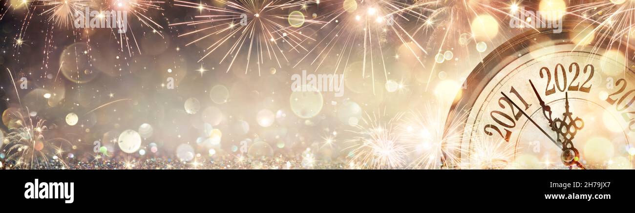 Año Nuevo 2022 - Cara de reloj dorada con fuegos artificiales y luces abstractas desfocadas Foto de stock