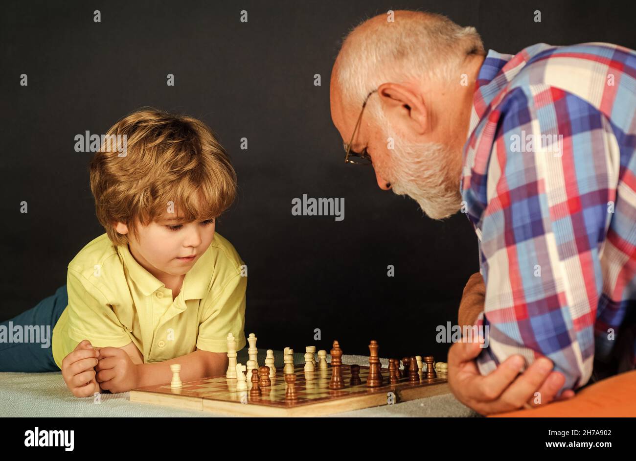 Relación familiar. El abuelo y el nieto juegan al ajedrez. Juego de mesa. Abuelo enseñando a nieta jugando ajedrez. Foto de stock
