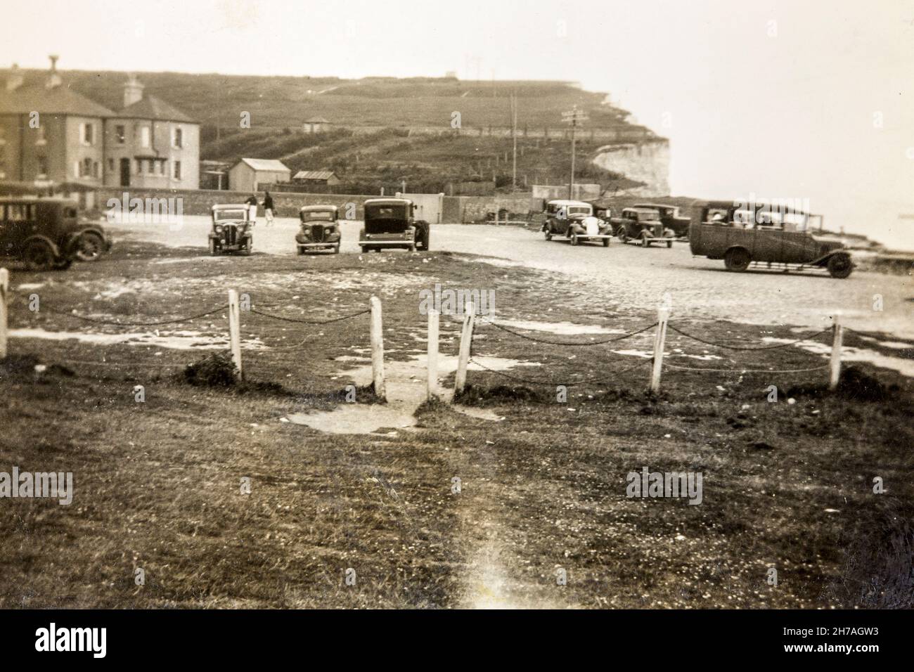 Fotografía tomada en la década de 1930 en Birling Gap, cerca de Eastbourne, E. Sussex. El borde del acantilado se ha erosionado a las casas de la izquierda. Foto de stock