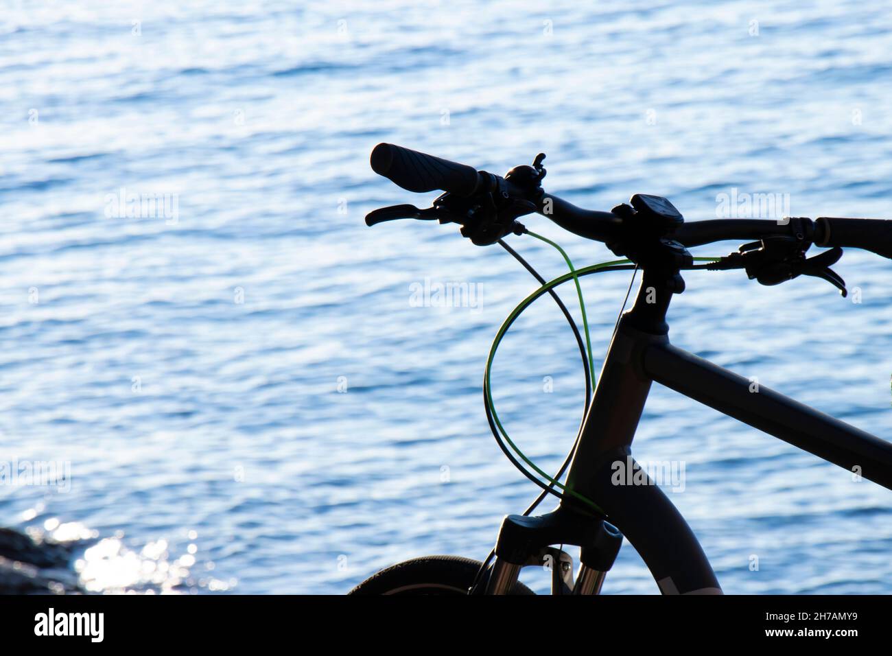 Bicicleta aparcada cerca de una playa a primera hora de la tarde, detalle de una rueda de estacionamiento Foto de stock