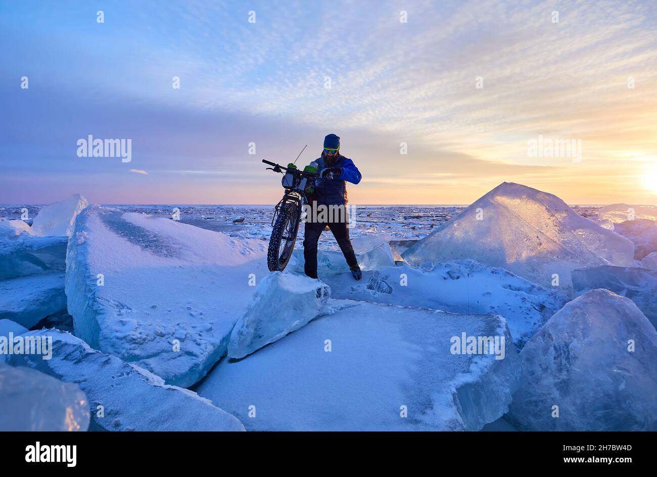 Hombre con bicicleta gorda en el lago congelado Kapchagay al atardecer en Kazajstán Foto de stock