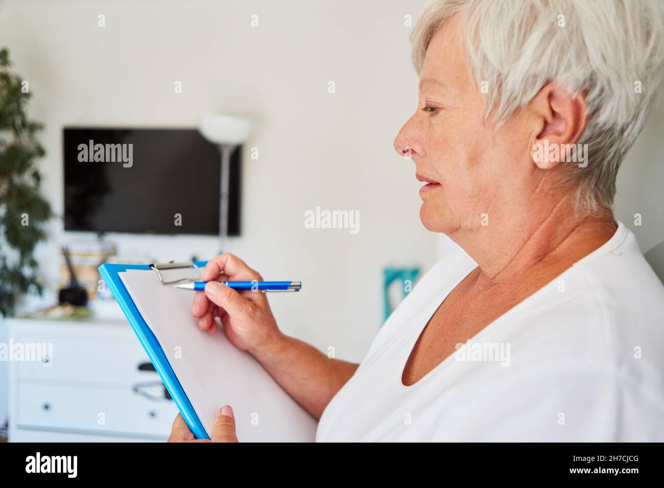 La supervisión del hogar utiliza una lista de verificación en el portapapeles para verificar la limpieza e higiene en el hogar de ancianos Foto de stock