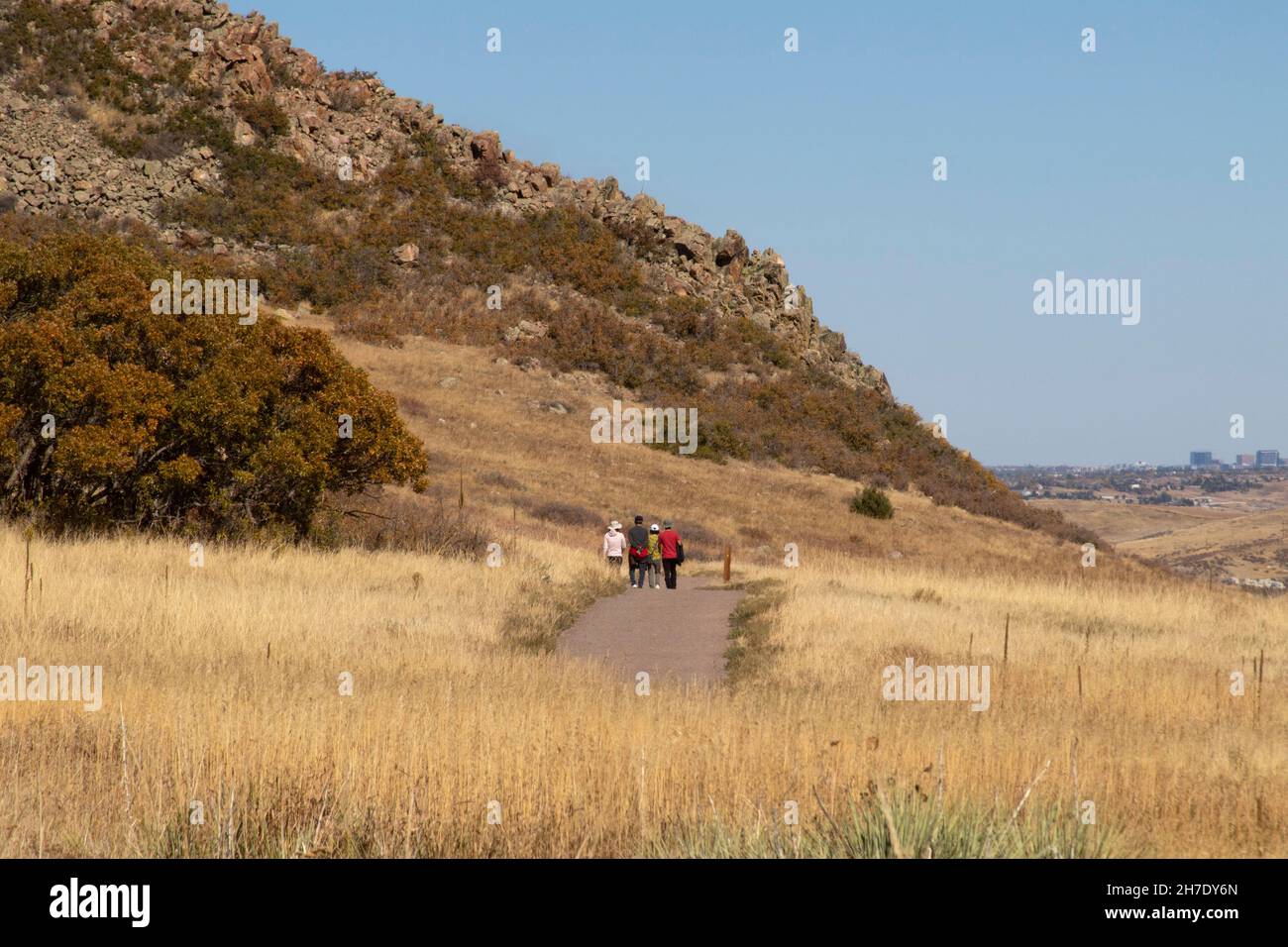 Los visitantes que utilizan un sendero bien mantenido en el Parque Estatal Roxborough pueden ver el horizonte de Denver, COLORADO. Foto de stock