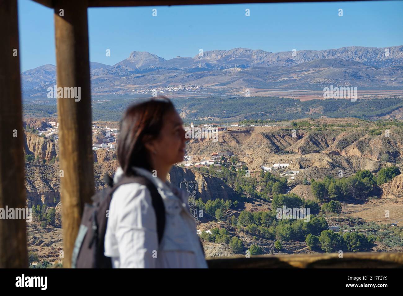Mujer desenfocada de 50 años con chubasquero y mochila admirando el paisaje de los badlands de Marchal (España) Foto de stock