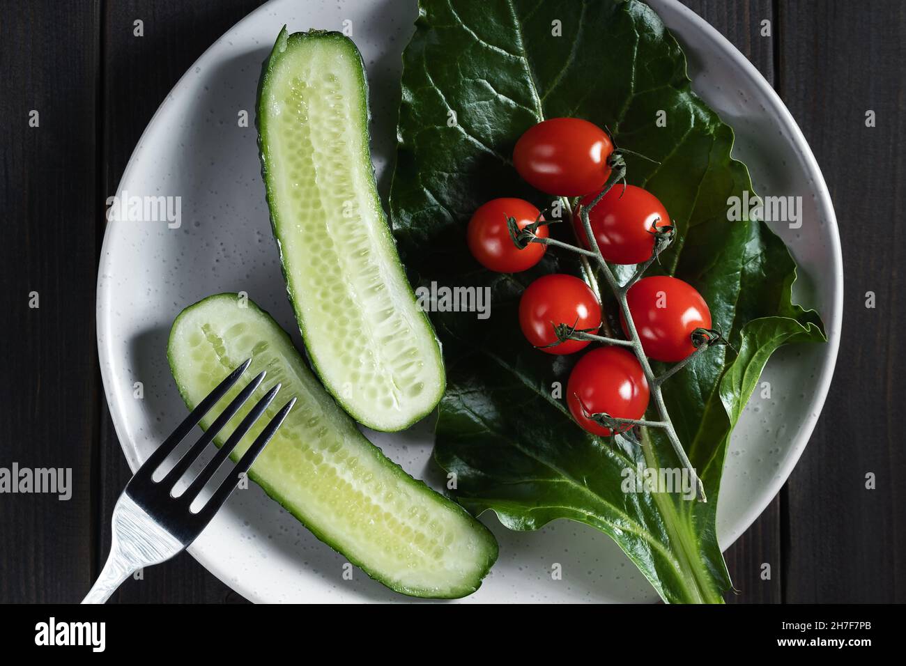 Verduras frescas y hierbas en un plato sobre una mesa de madera. Concepto de vegetarianismo y alimentación saludable. Foto de stock