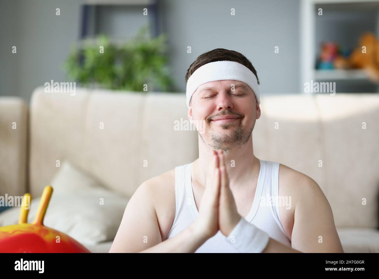 El hombre de mediana edad meditando en casa puso las manos en el gesto namaste Foto de stock