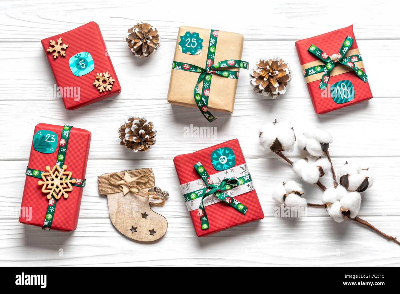 Cajas de regalo rojas, verdes envueltas a mano decoradas con cintas, copos  de nieve y números, decoraciones de Navidad y decoración sobre mesa blanca  de Advenimiento de Navidad Fotografía de stock -