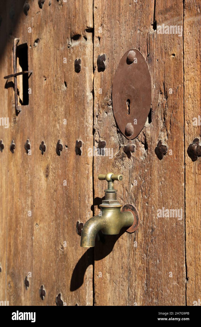 Grifo de agua de latón sólido, grifo en una puerta de madera. Foto de stock