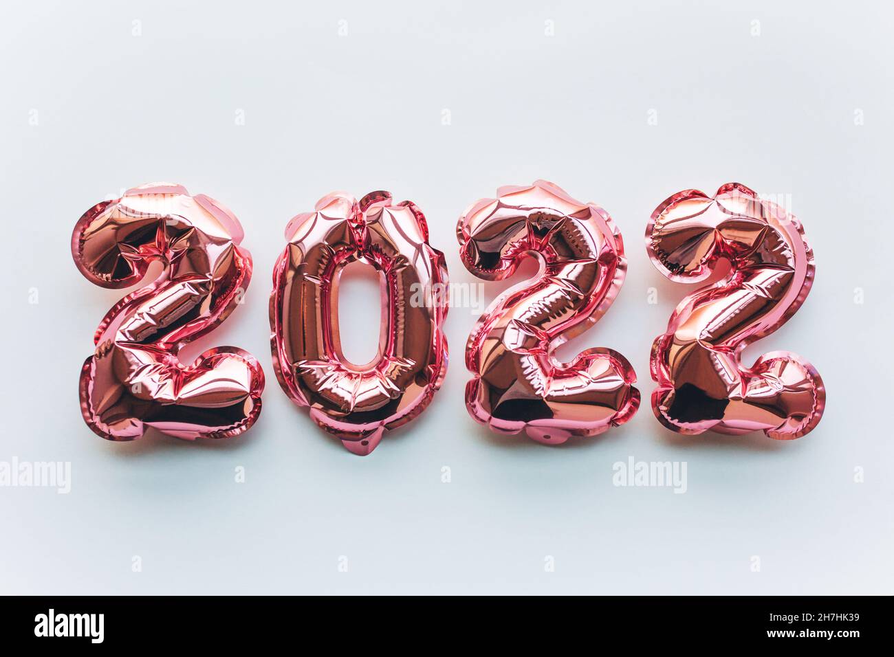 Globos hechos de papel de aluminio rosa en forma de números 2022 sobre fondo blanco . Celebración de Navidad, Año Nuevo y concepto festivo. Plano, vista superior. Foto de stock