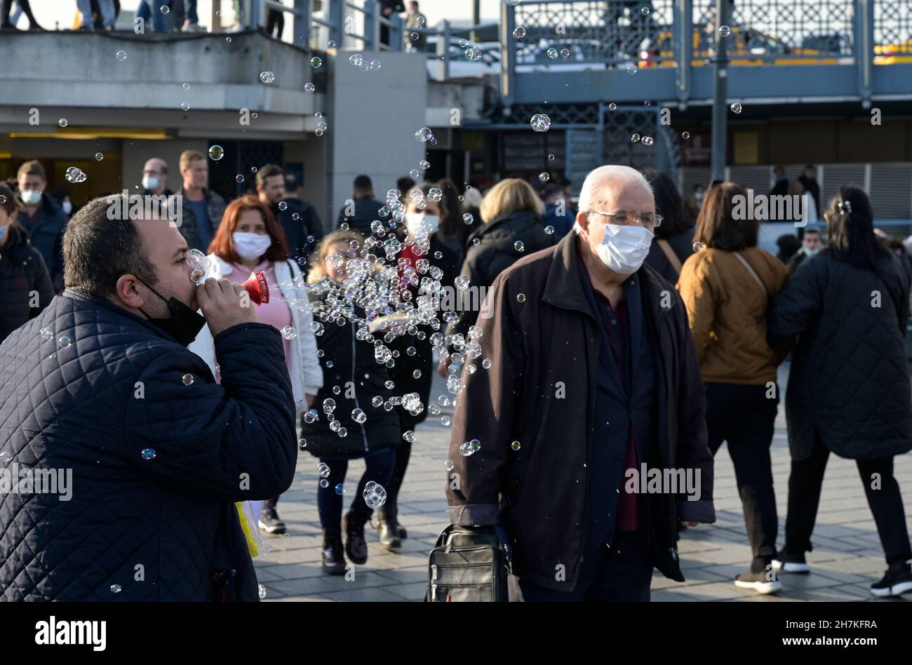 TURQUÍA, Estambul, estación de ferry de Eminönü, pandemia de corona, personas con máscaras faciales, vendedor de burbujas de jabón / Türkei, Estambul, Stadtteil Eminönü Fähranleger, Corona Pandemie, Passanten mit Masken Foto de stock