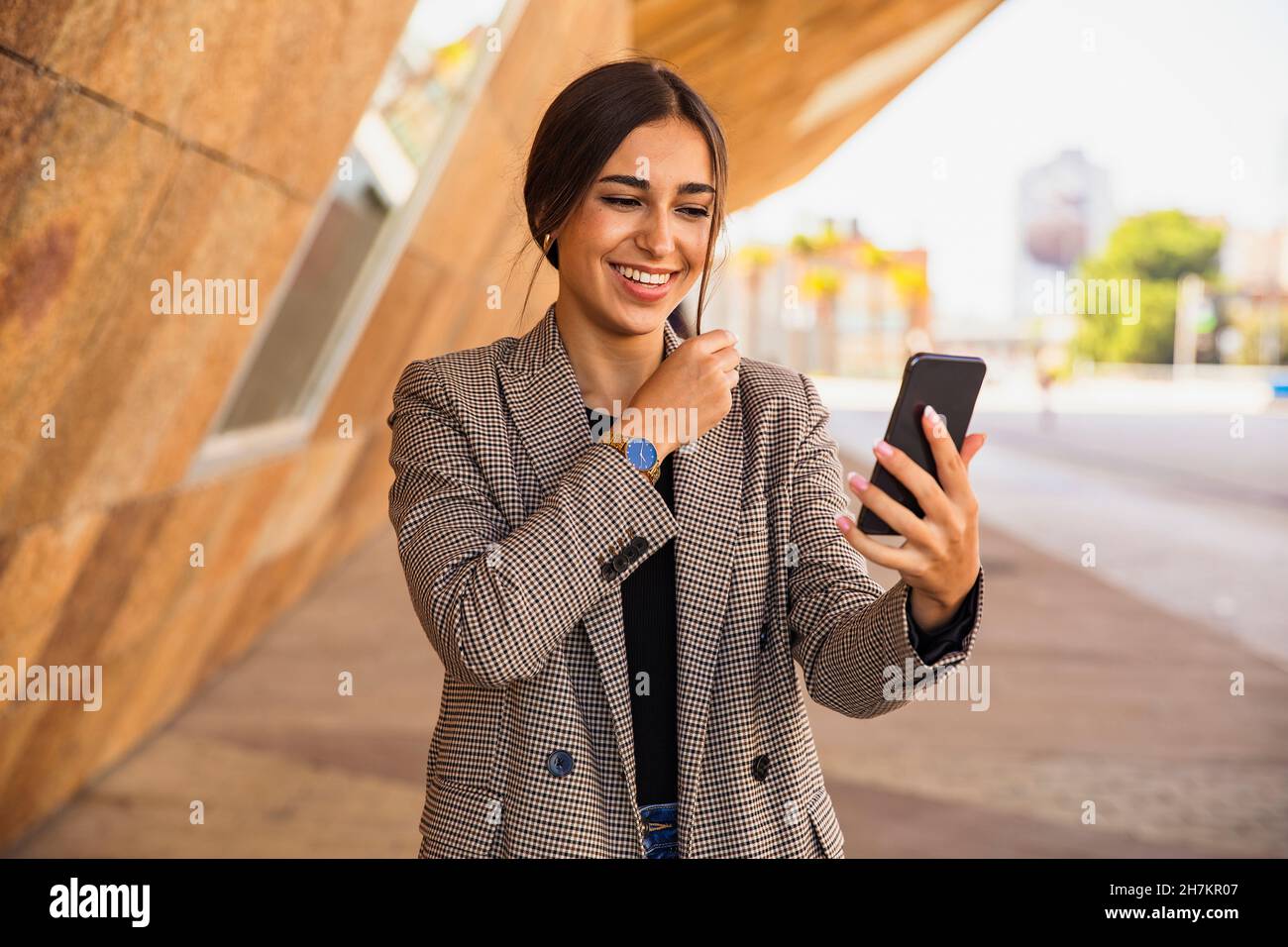 Feliz mujer de negocios hablando durante la videoconferencia a través del teléfono móvil en el sendero Foto de stock