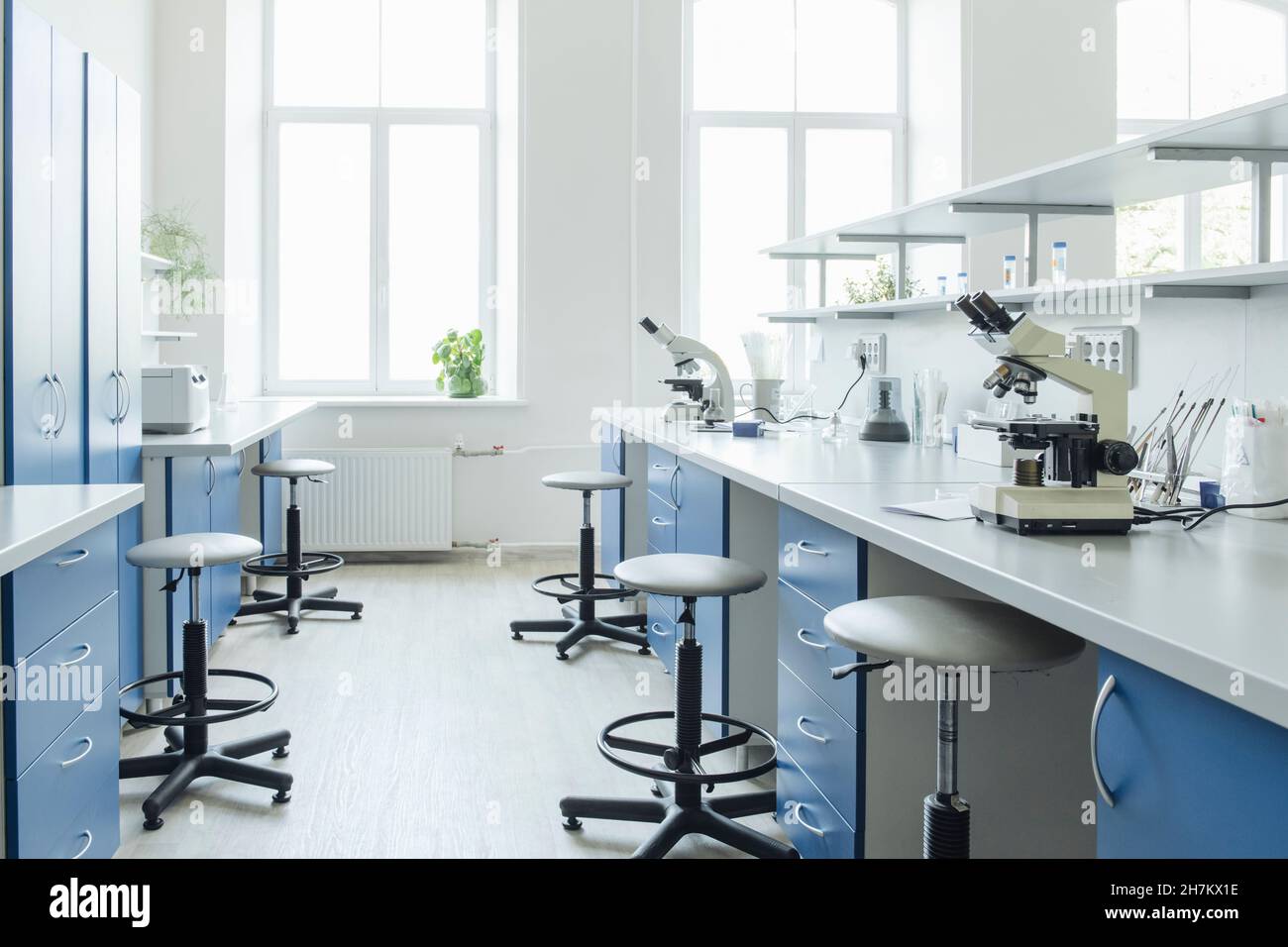 Microscopios en el escritorio en un laboratorio vacío y luminoso Foto de stock