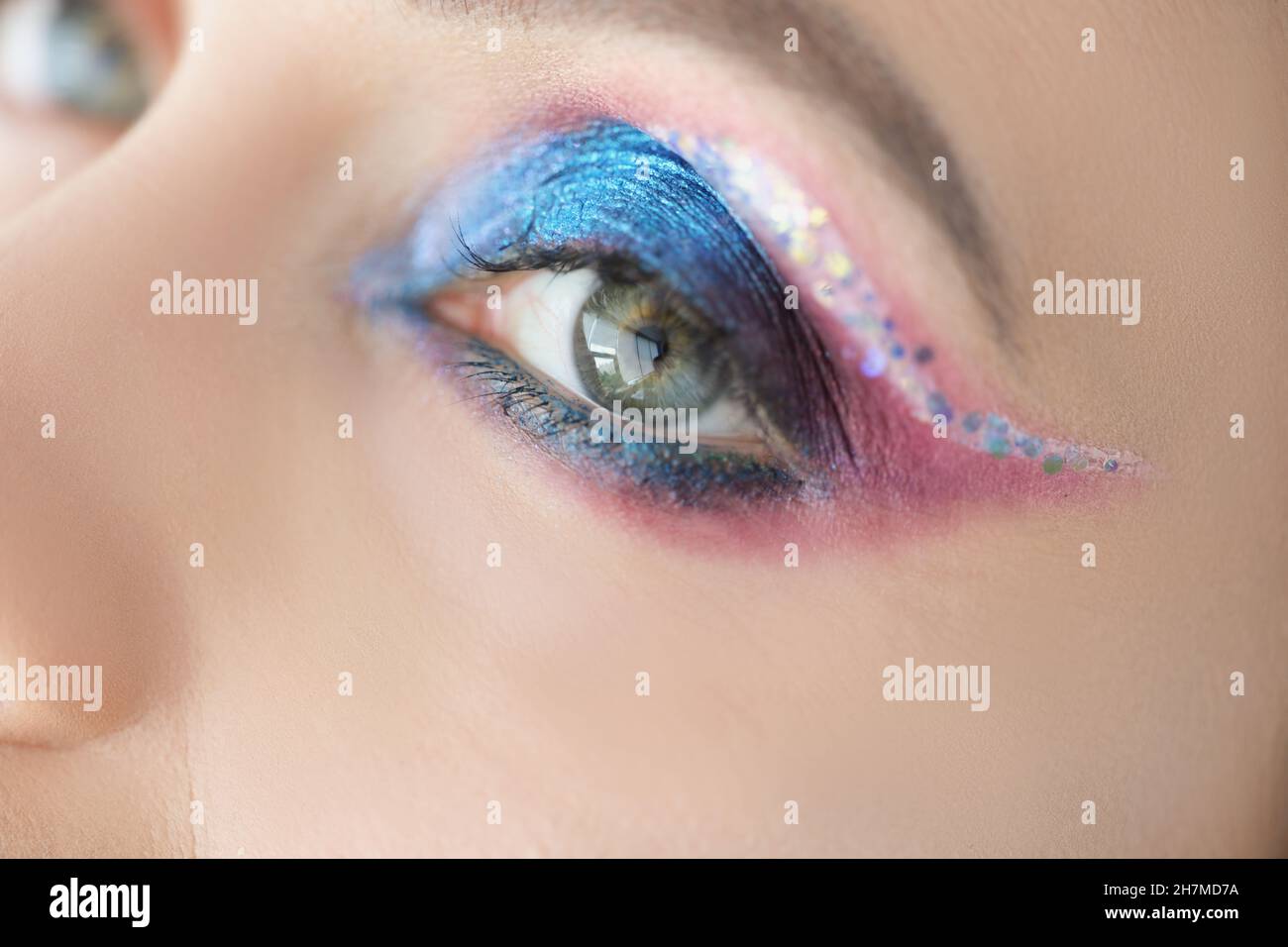 Maquillaje festivo para ojos brillantes en la cara de las mujeres con purpurina azul y rosa Foto de stock