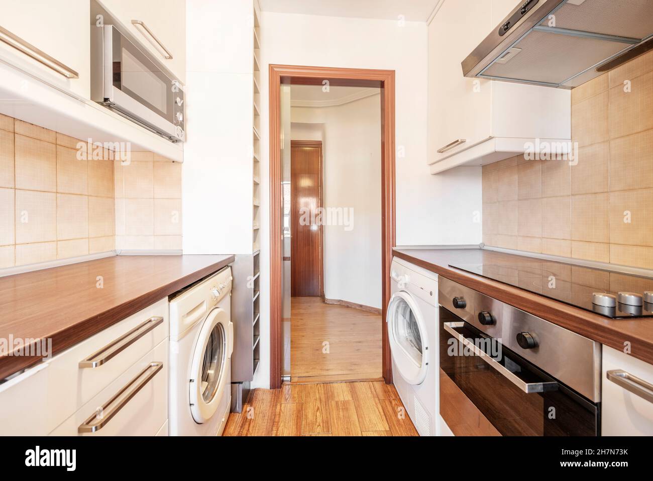 Cocina con encimera de madera, lavavajillas abierto, vitrocerámica, horno y  lavadora con suelo de madera oscura en el apartamento de alquiler  Fotografía de stock - Alamy