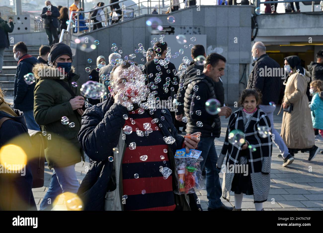 TURQUÍA, Estambul, estación de ferry de Eminönü, pandemia de corona, personas con máscaras faciales, vendedor de burbujas de jabón / Türkei, Estambul, Stadtteil Eminönü Fähranleger, Corona Pandemie, Verkäufer mit Seifenblasen Spielzeug und Passanten mit Masken Foto de stock