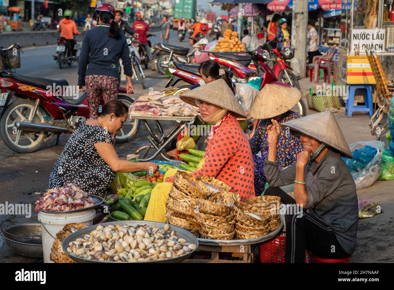 CAN Tho, Vietnam-5 de abril de 2018: Las mujeres con sombrero cónico tradicional venden frutas y verduras en la calle de Can Tho. Foto de stock