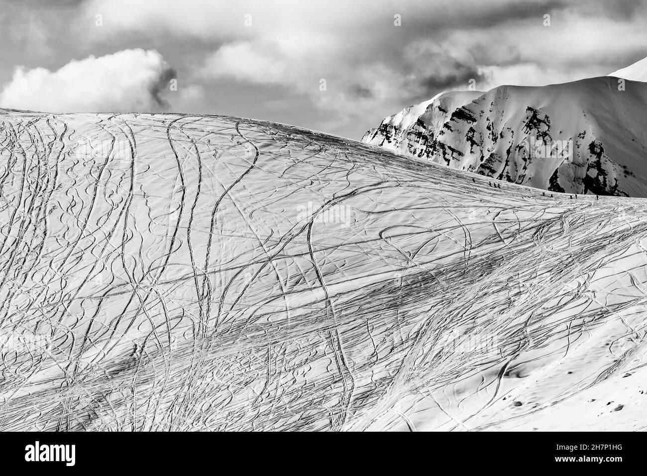 Nieve en pista para freeriding con rastros de esquís, snowboards en el soleado día de invierno. Montañas del Cáucaso, Georgia, región Gudauri. Negro y blanco Foto de stock