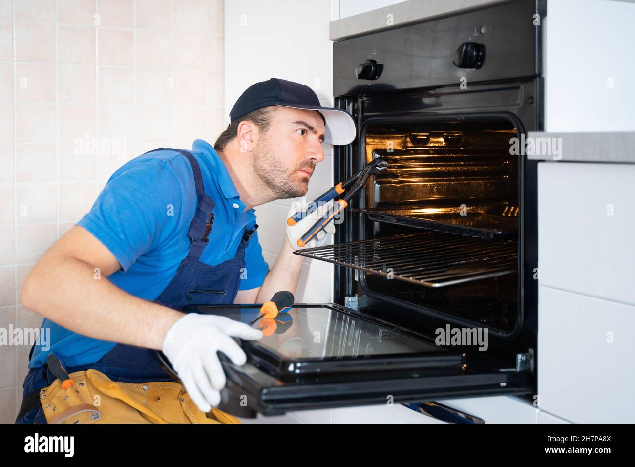 Un reparador arregla un problema de horno de cocina que no funciona  correctamente Fotografía de stock - Alamy