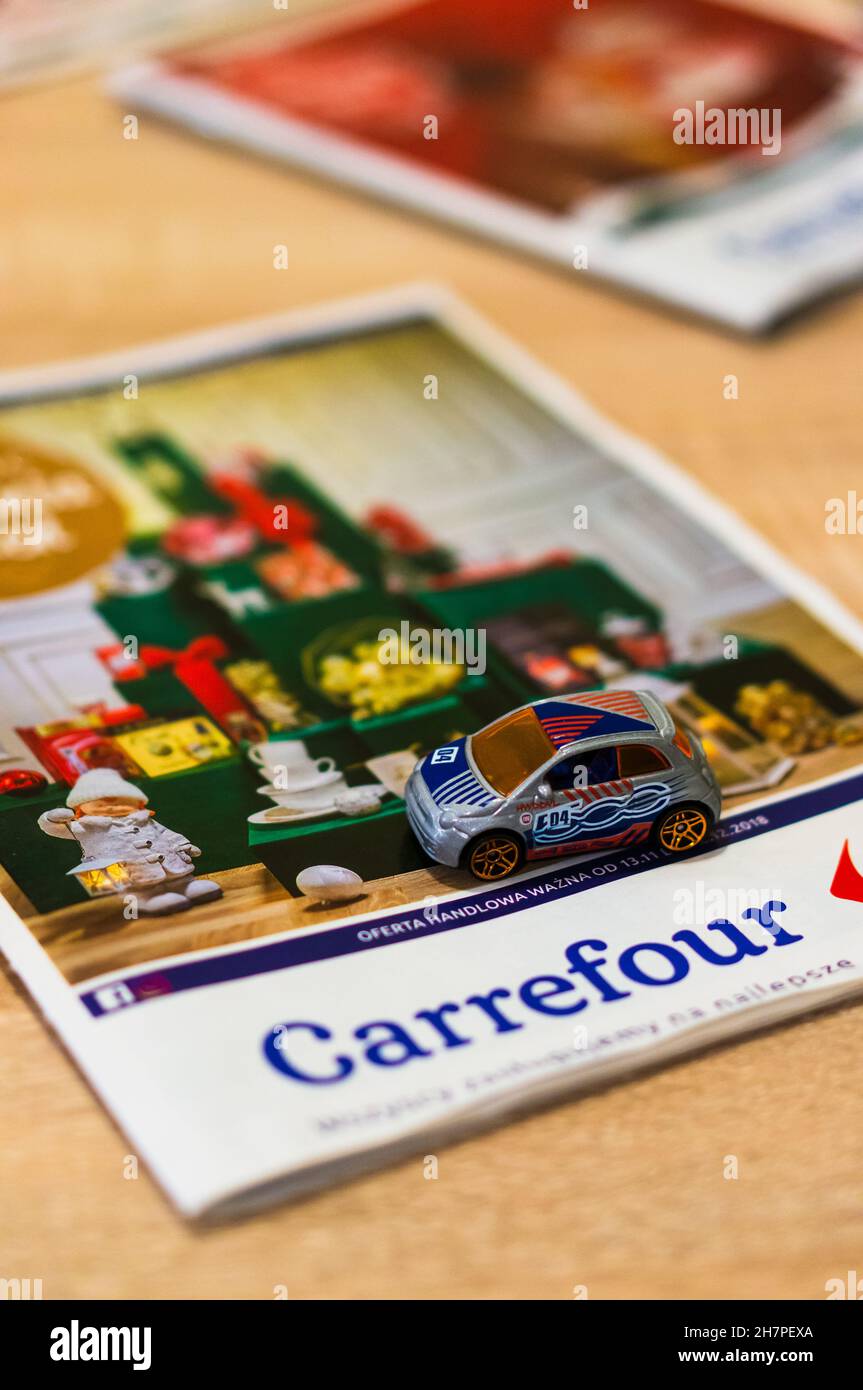 POZ, POLONIA - 17 de noviembre de 2018: Un coche de juguete Fiat 500 en un folleto Carrefour con un tema de Navidad Fotografía de stock -