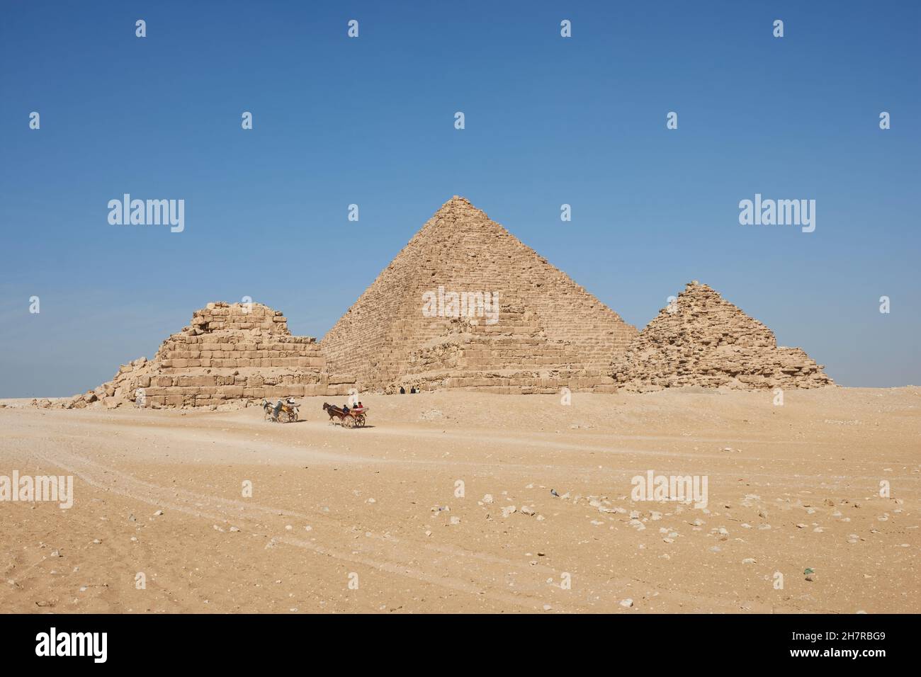 Carros tirados por caballos cerca de las pirámides de Giza. Menkaure y las reinas pirámides se ven desde el desierto Foto de stock