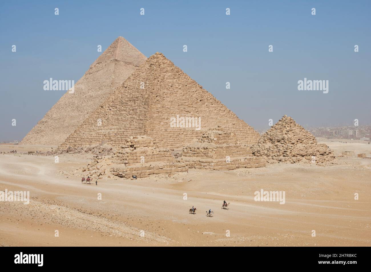Vista de Khafre, Menkaure y pirámides de Queens desde el desierto. Varios jinetes de caballos y camellos en el marco. Foto de stock
