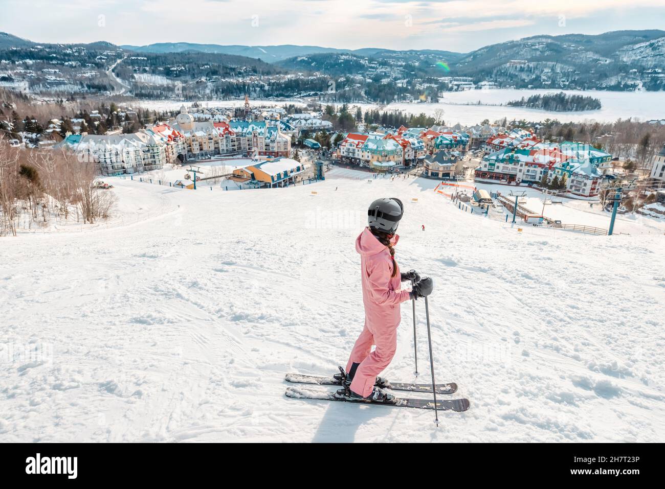 Mujer de esquí. Esquí alpino - vista de la estación de esquí de pueblo de montaña que mira a un esquiador empezando a esquiar cuesta abajo en pistas de esquí cubiertas de nieve en invierno. Mont Foto de stock