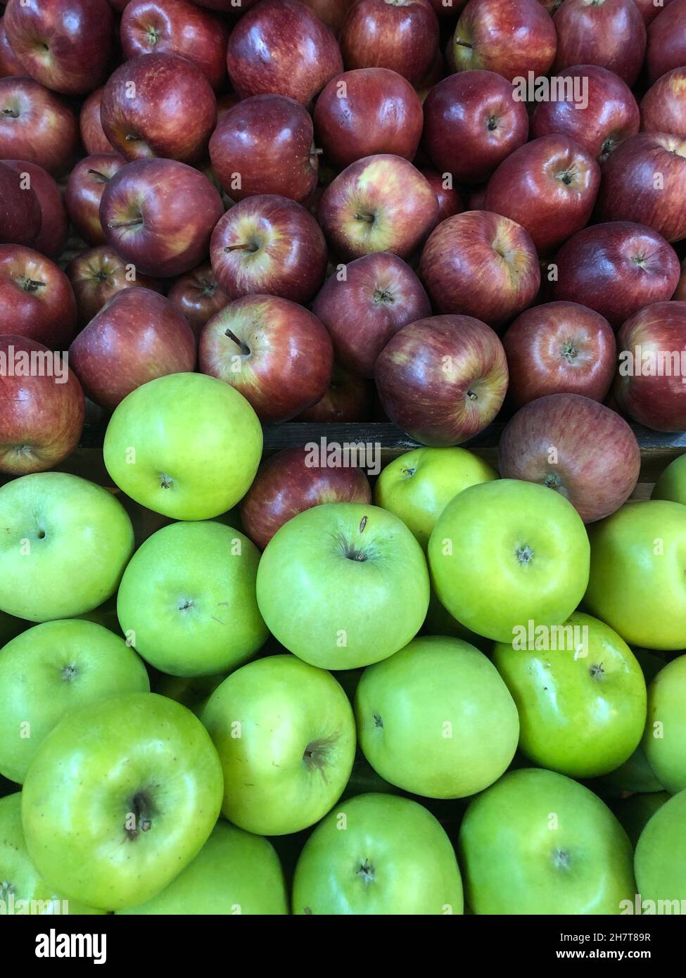 varias manzanas rojas y verdes a la venta en un mercado al aire libre. Foto de stock